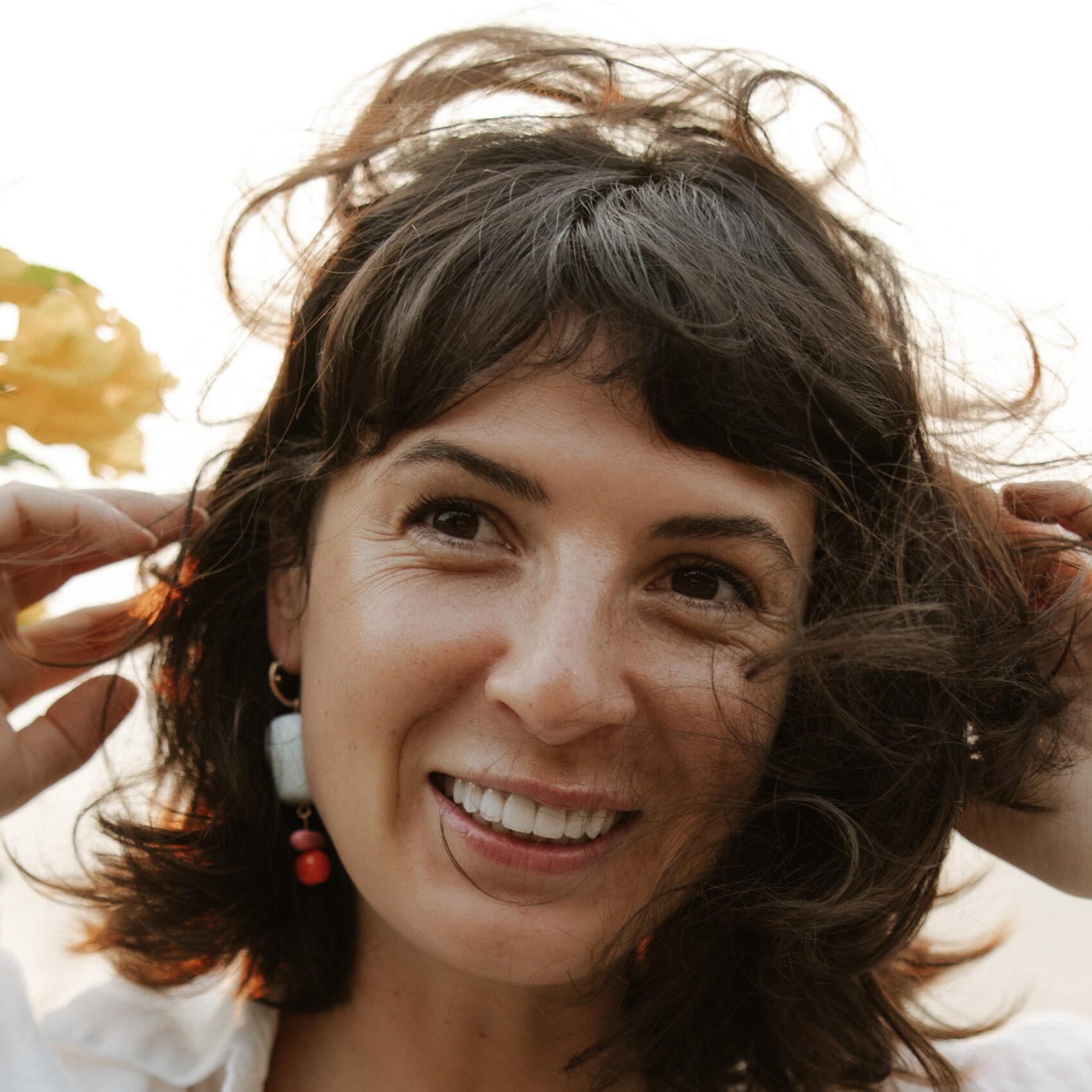 femme brune qui sourit en se touchant les cheveux
